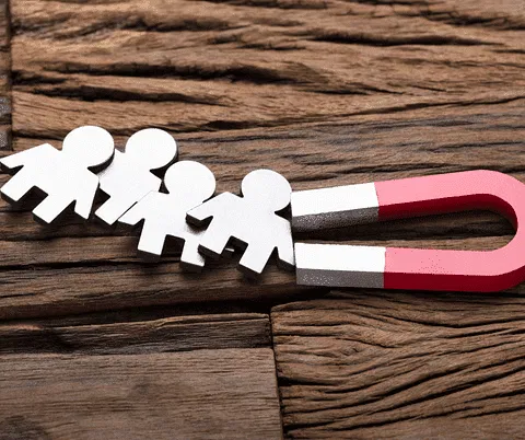 A red and white horseshoe magnet pulls four paper cut-out people, highlighting the attraction of a hyperlocal digital marketing agency in Pune. - IPSense.com